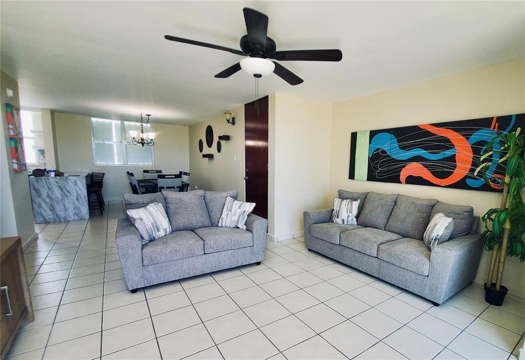 A living room features two gray sofas, tile flooring, and a ceiling fan — La Loma 104, FAJARDO, PR