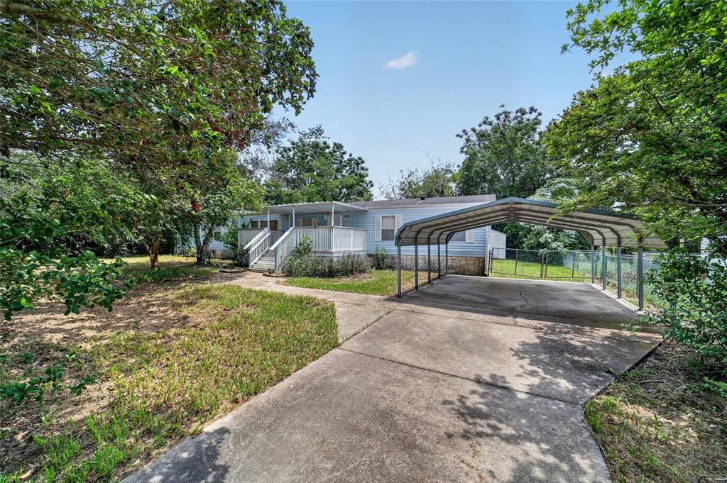 A light blue manufactured home with a front deck and a metal carport on concrete — 14085 SE 59TH COURT, SUMMERFIELD, FL