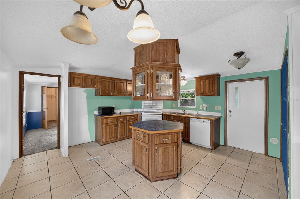 A kitchen with wood cabinets, a central island, tile flooring, and light green walls — 14085 SE 59TH COURT, SUMMERFIELD, FL