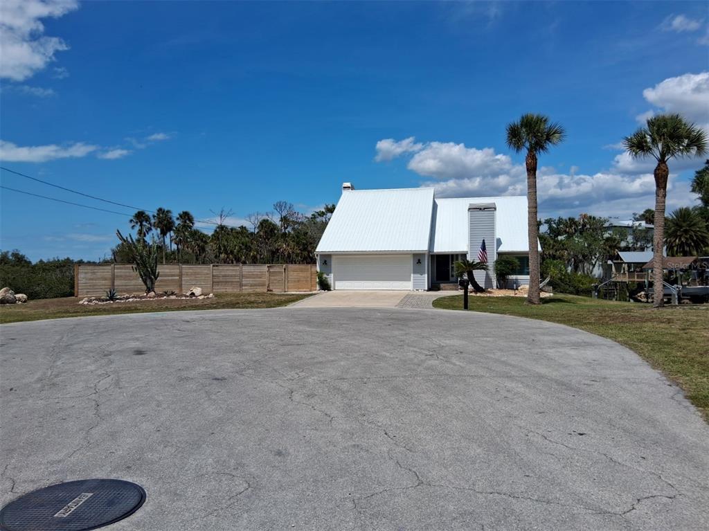 A rectangular swimming pool sits alongside a gray house with a chimney and wooden fence — 8720 BETTY STREET, PORT RICHEY, FL