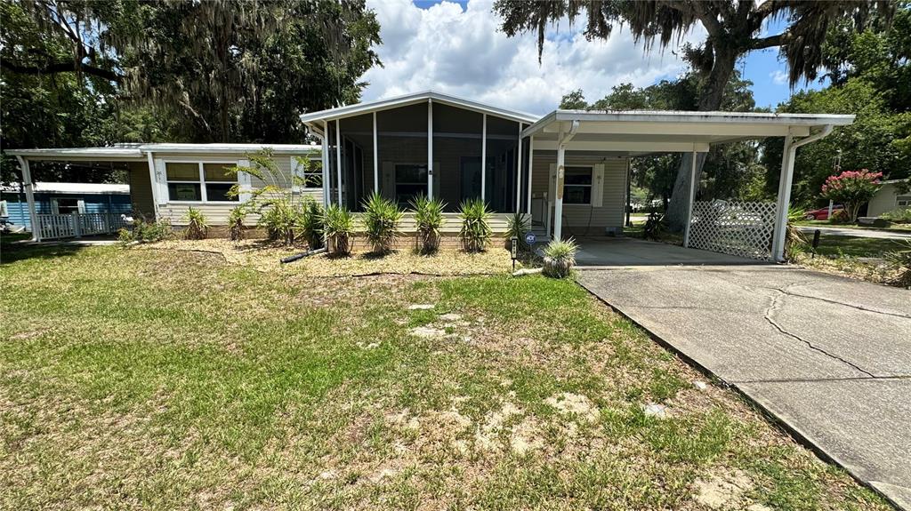 A single-story manufactured home features a screened-in front porch, a carport, and a concrete driveway — 1913 NW 47TH TERRACE, OCALA, FL