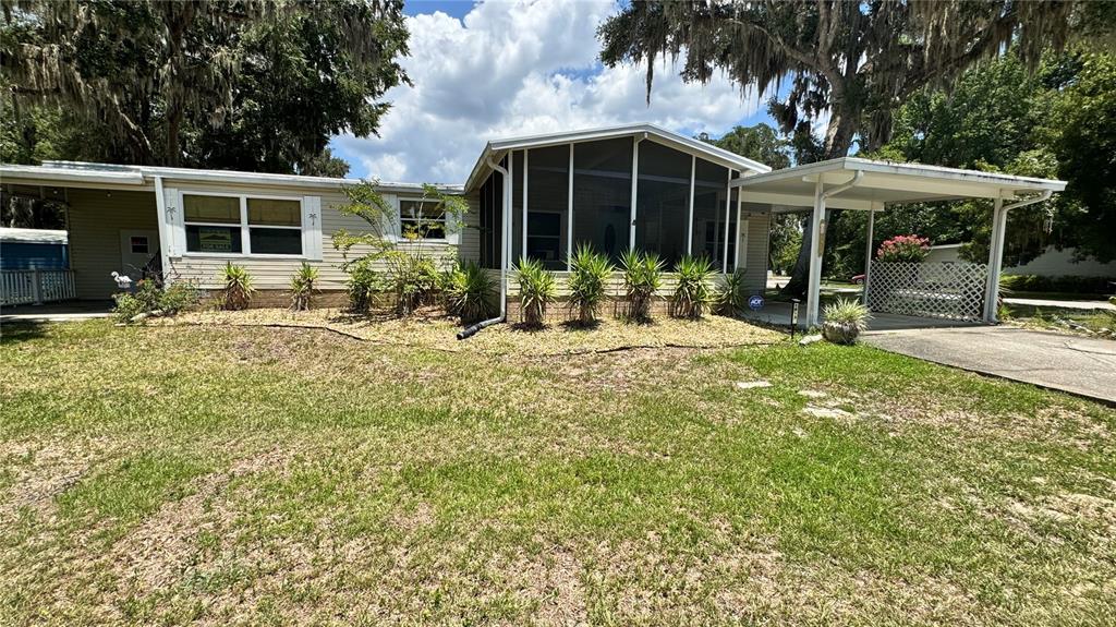 A single-story house with a screened-in porch, a carport, and a grassy front yard — 1913 NW 47TH TERRACE, OCALA, FL