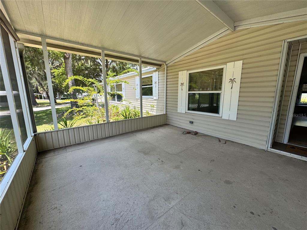 A screened-in porch with a concrete floor and beige vinyl siding on the exterior wall — 1913 NW 47TH TERRACE, OCALA, FL