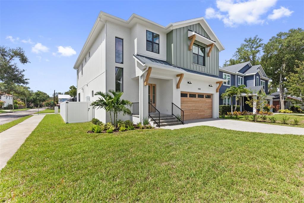 A two-story house with white brick, vertical siding, and a wooden garage door — 4302 W OBISPO STREET, TAMPA, FL