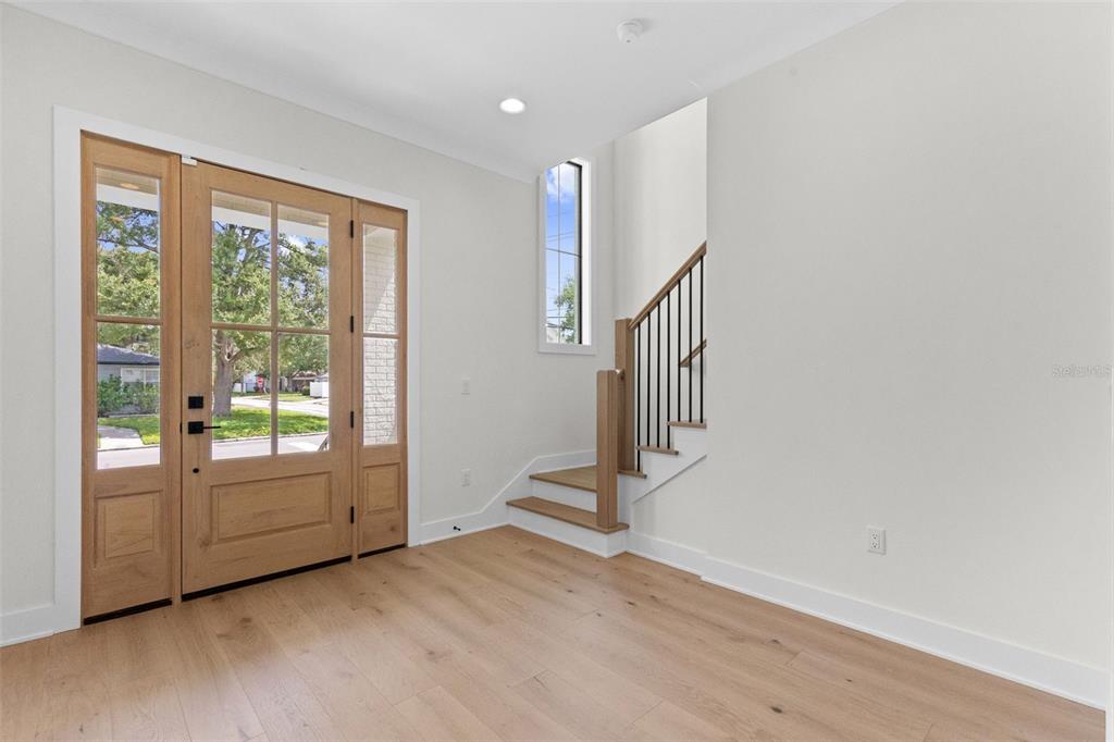 An entryway features light wood flooring, a wooden front door, and a staircase with railings — 4302 W OBISPO STREET, TAMPA, FL
