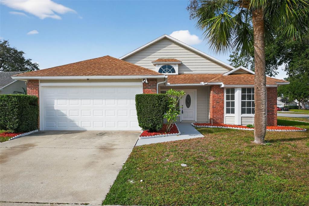 A single-story house with a brick and siding facade, a two-car garage, and a palm tree — 233 S ABERDEEN CIRCLE, SANFORD, FL