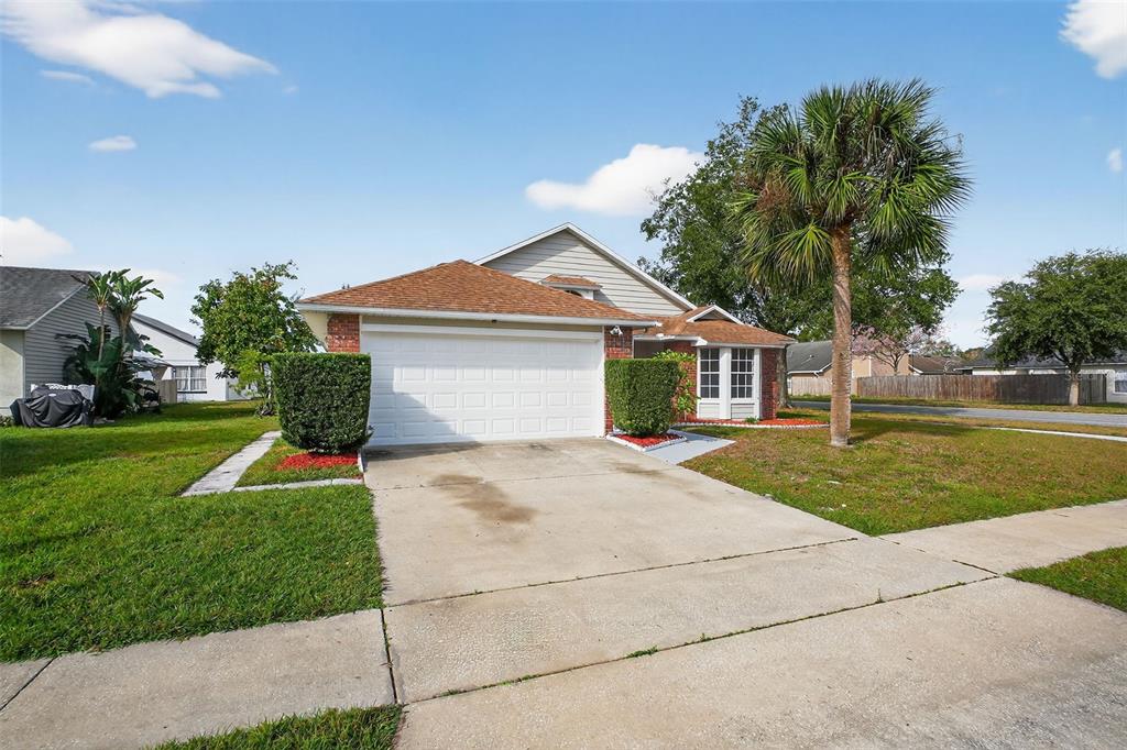 A single-story house with a white garage door, tan siding, and a palm tree — 233 S ABERDEEN CIRCLE, SANFORD, FL