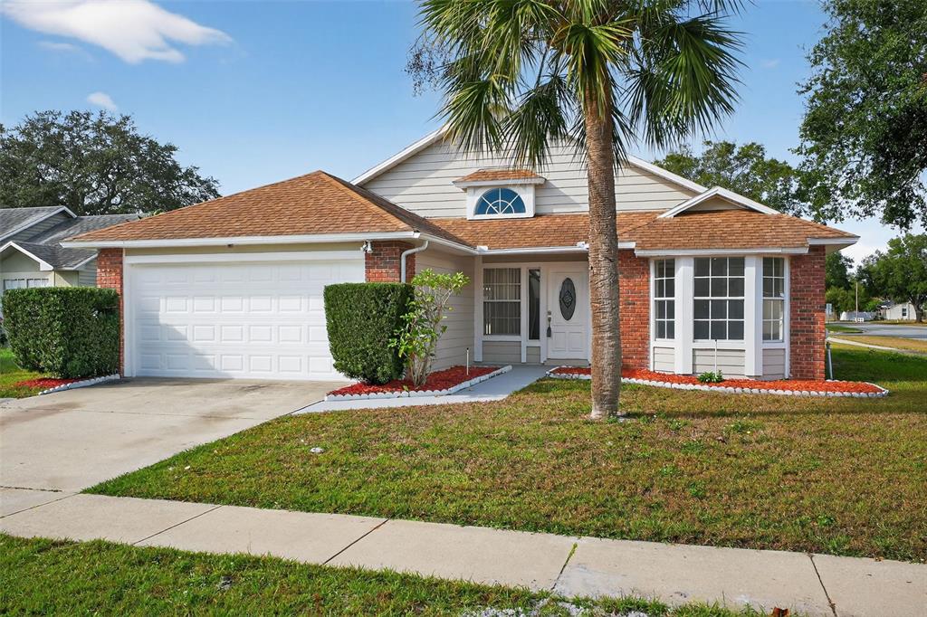 A single-story suburban house with a two-car garage, brick accents, and a front palm tree — 233 S ABERDEEN CIRCLE, SANFORD, FL
