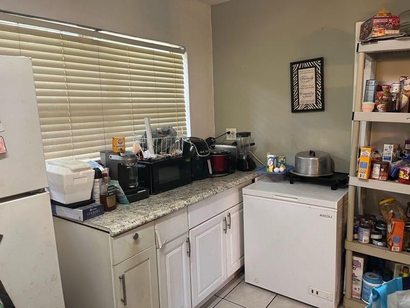 A kitchen features white cabinets, granite countertops, a chest freezer, and various small appliances — 1528 STEVENSONS DRIVE, CLEARWATER, FL