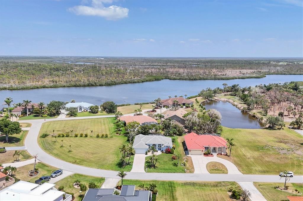 An aerial view shows several suburban houses with pools near a large body of water — 11 AMBERJACK LANE, PLACIDA, FL