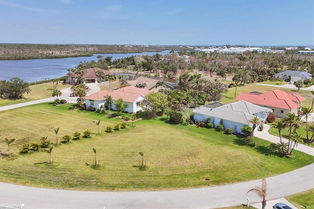 An aerial view shows a vacant grassy lot situated between several houses near a waterway — 11 AMBERJACK LANE, PLACIDA, FL