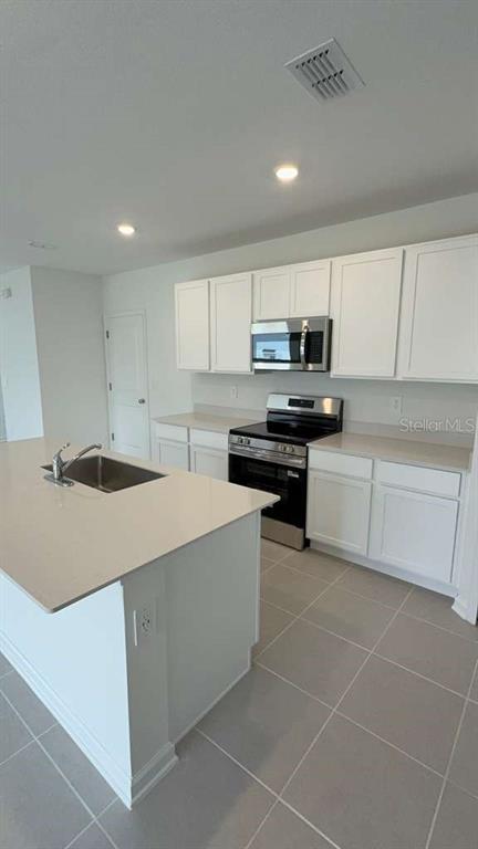 A modern kitchen features white cabinets, stainless steel appliances, and a large central island — 3619 HARDMAN DRIVE, LAKE WALES, FL