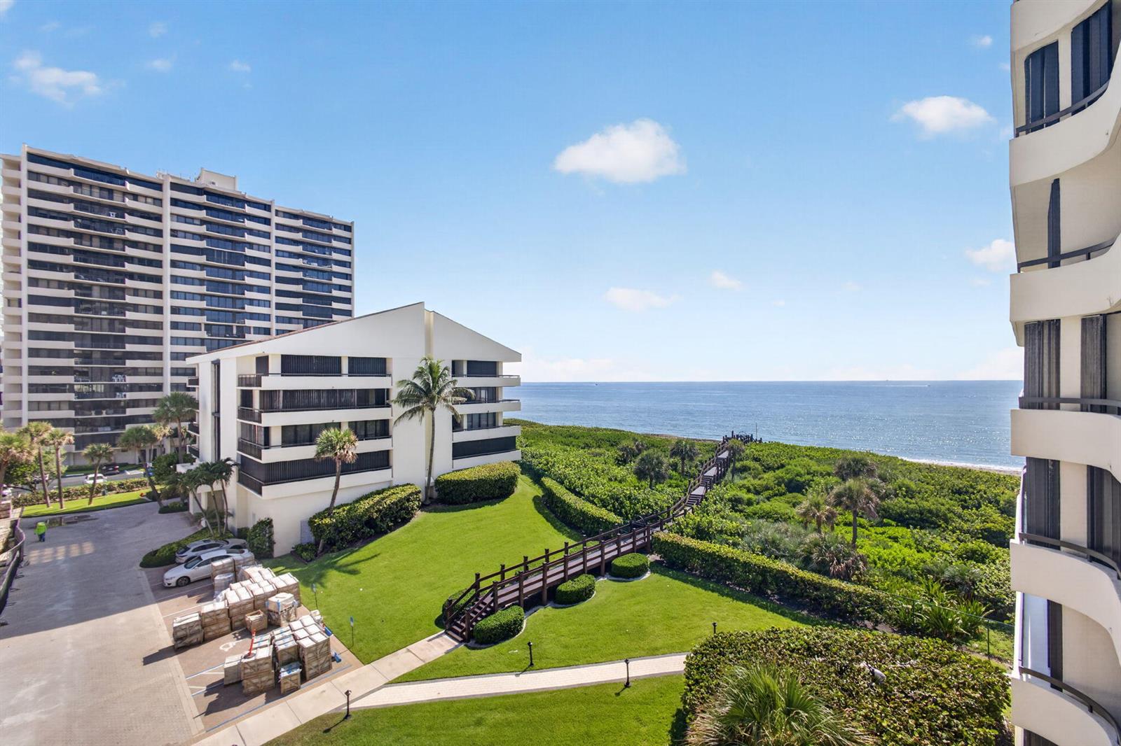 An elevated view of a coastal property featuring a lawn, wooden walkway, and ocean view — 4000 N Ocean Drive # 403, Singer Island FL 33404, SINGER ISLAND, FL