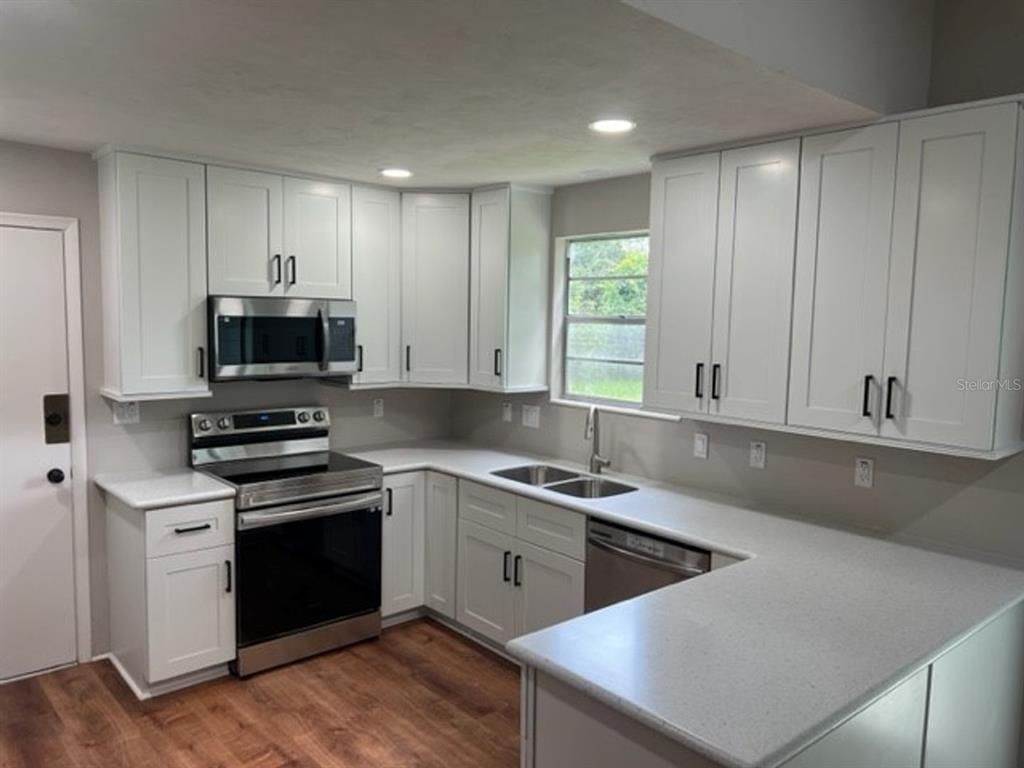 A kitchen features white shaker cabinets, stainless steel appliances, and light-colored quartz countertops — 6613 NW 30TH TERRACE, GAINESVILLE, FL