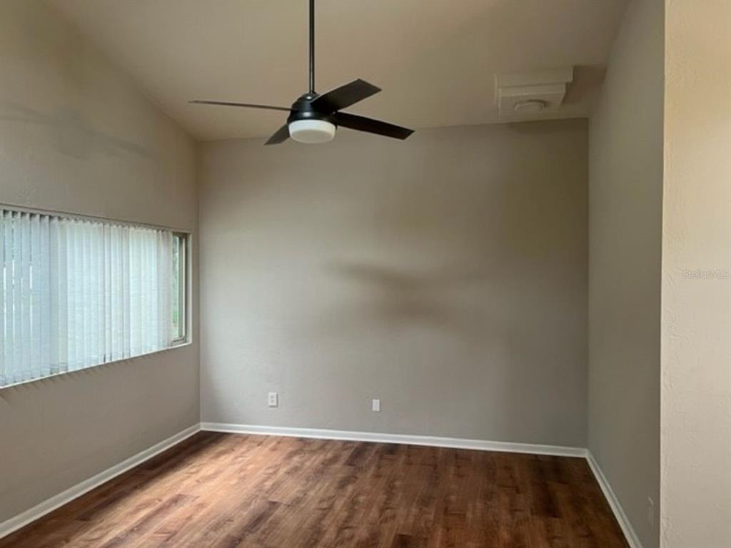 An empty room with wood-look flooring, a ceiling fan, and a window with blinds — 6613 NW 30TH TERRACE, GAINESVILLE, FL
