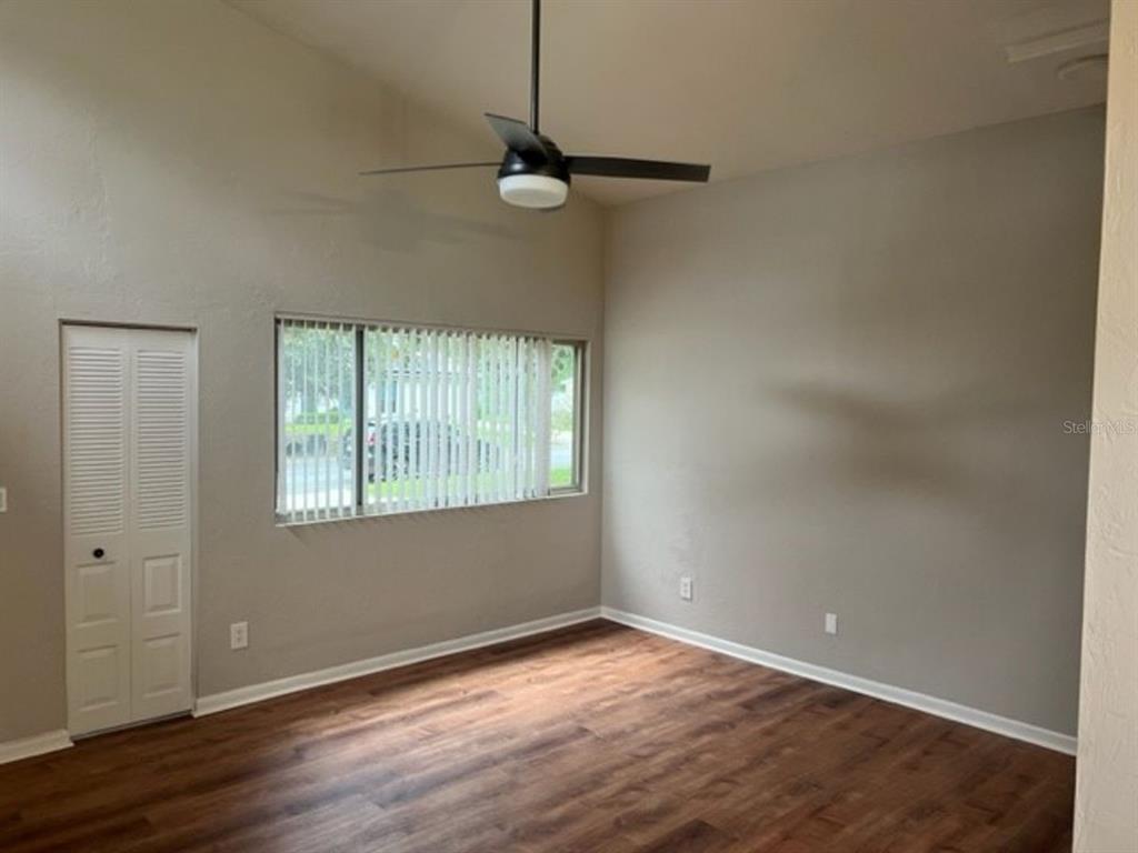 An empty room features wood-look flooring, a ceiling fan, and a window with vertical blinds — 6613 NW 30TH TERRACE, GAINESVILLE, FL