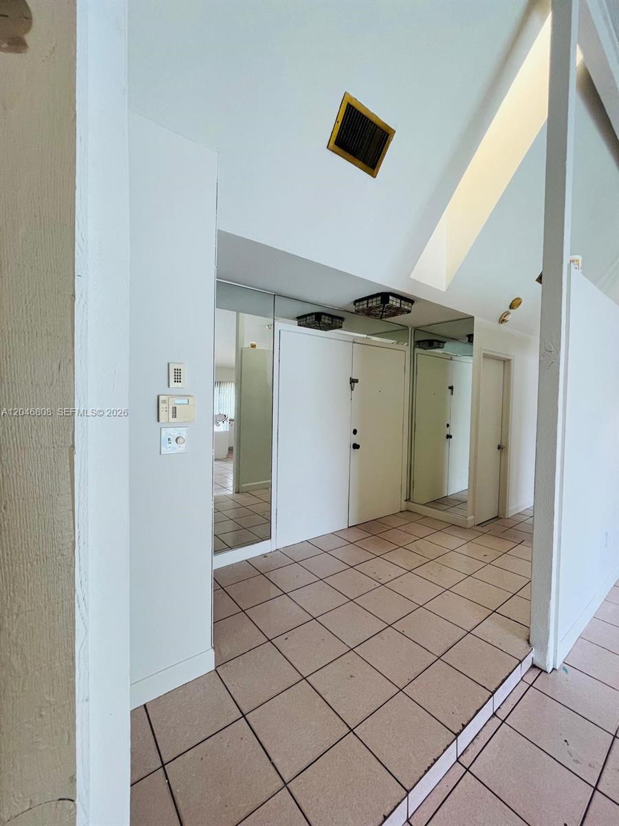 An entryway features tiled floors, mirrored walls, and a high vaulted ceiling — 925 NE 207th Ter # 0, Miami FL 33179, MIAMI, FL