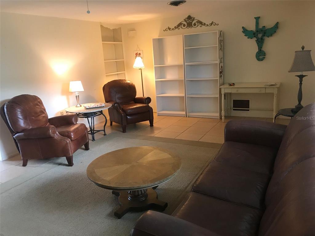 A living room features leather furniture, a round coffee table, white bookshelves, and tiled floors — 1825 SHADOW LANE, ENGLEWOOD, FL