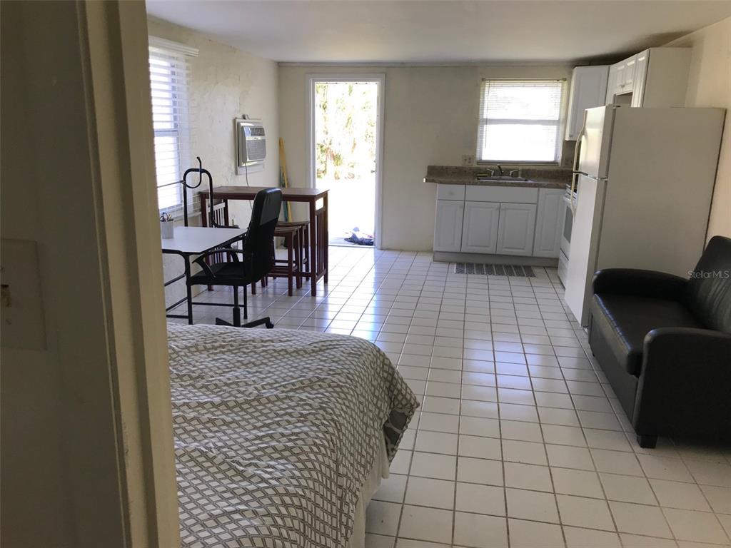 A studio apartment features a bed, a small kitchen, a dining area, and tiled floors — 1825 SHADOW LANE, ENGLEWOOD, FL