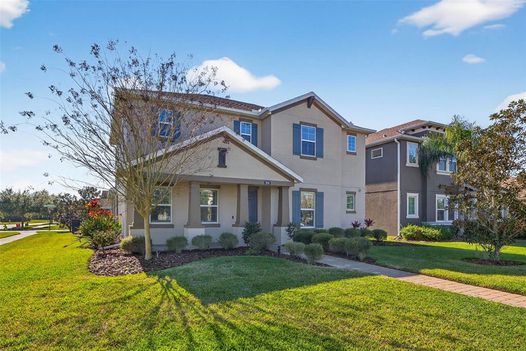A two-story suburban house with a tan stucco exterior, blue shutters, and a front porch — 17268 BRIGHTON LAKE ROAD, LAND O LAKES, FL