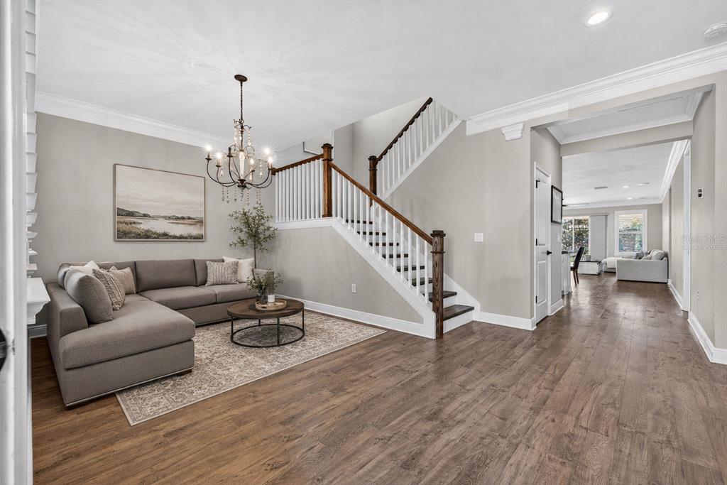 A living room with a sectional sofa, a staircase, and wood-look flooring — 17268 BRIGHTON LAKE ROAD, LAND O LAKES, FL
