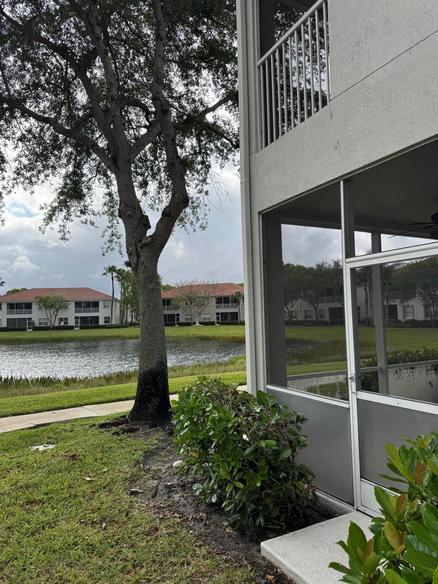 A view of a lake and apartment buildings from a ground-floor screened-in patio — 2140 Wingate Bend, Wellington FL 33414, WELLINGTON, FL