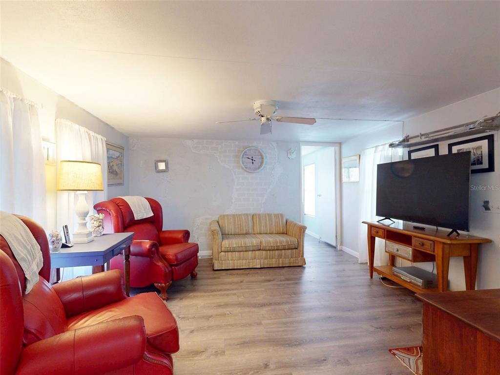 A living room features red leather recliners, a striped sofa, and a television on a stand — 2201 S RIDGEWOOD AVENUE UNIT 8, EDGEWATER, FL
