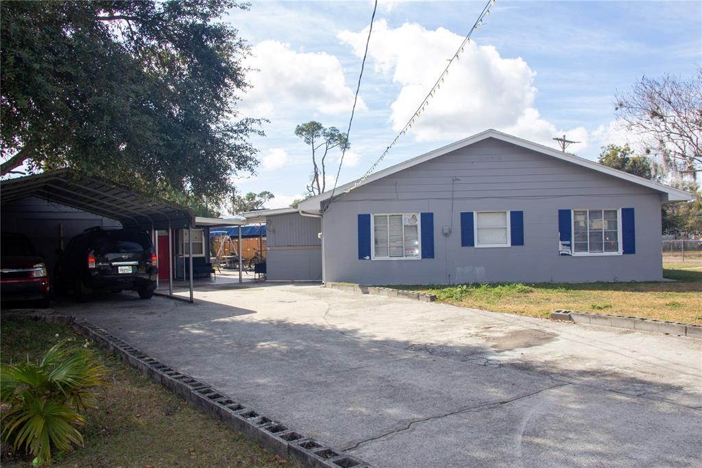 A single-story gray house with blue shutters features a concrete driveway and a metal carport — 2403 GOLFVIEW STREET, LAKELAND, FL