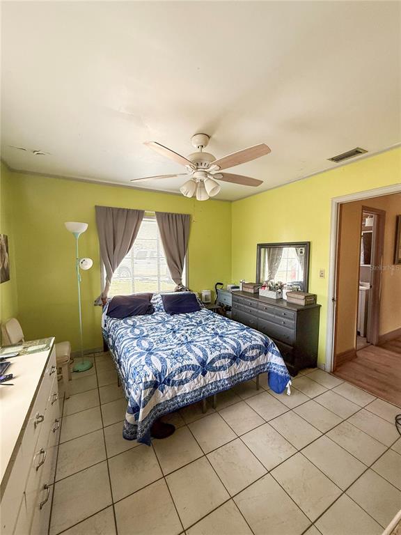 A bedroom features lime green walls, a ceiling fan, a bed with a blue quilt, and tile flooring — 2403 GOLFVIEW STREET, LAKELAND, FL