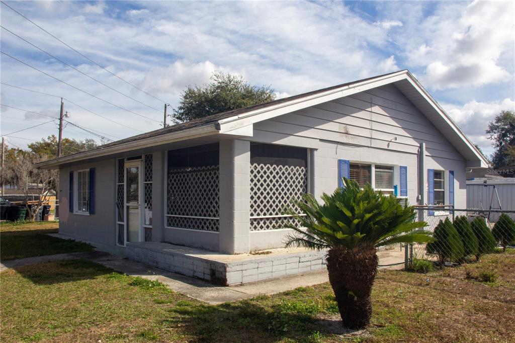 A single-story house with gray siding, a screened-in porch, and a small palm tree — 2403 GOLFVIEW STREET, LAKELAND, FL
