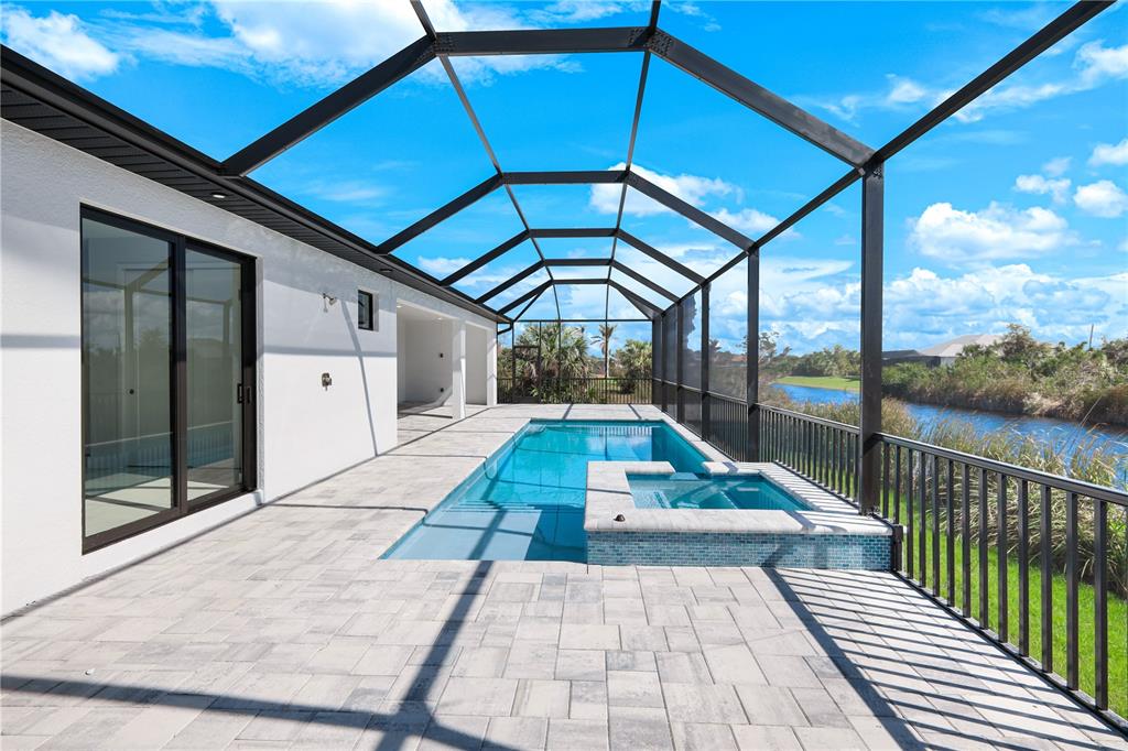 A screened-in patio features a swimming pool, a raised spa, and light-colored paver flooring — 14431 ARTESIA AVENUE, PORT CHARLOTTE, FL