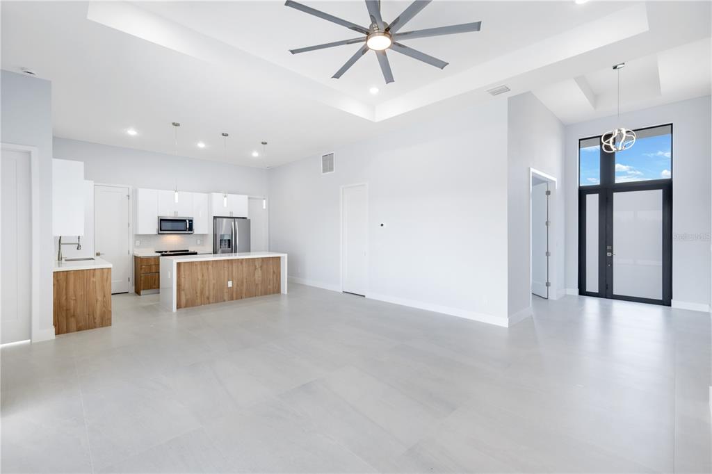 A modern open-concept kitchen and living area with white cabinets, wood-tone island, and tile flooring — 14431 ARTESIA AVENUE, PORT CHARLOTTE, FL