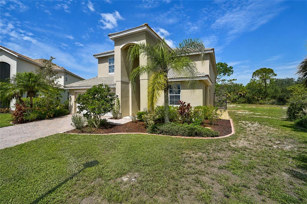 A two-story stucco house with a tiled roof, arched entryway, and landscaped front yard — 11691 BREADFRUIT LANE, VENICE, FL