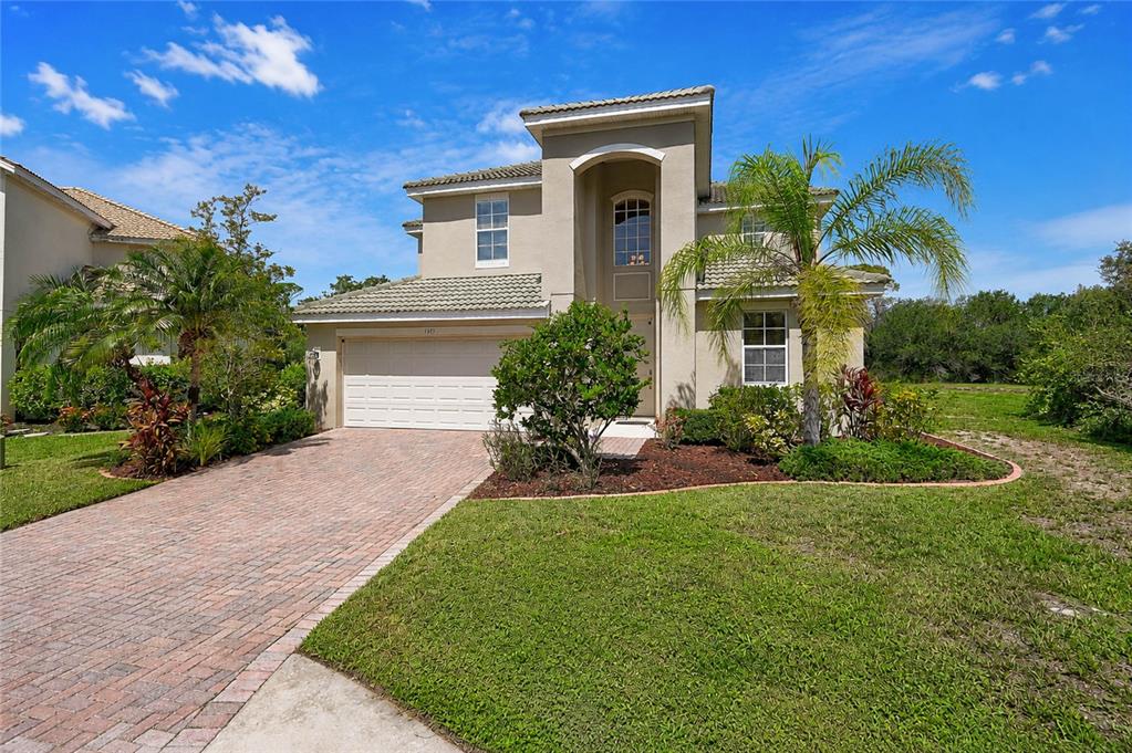 A two-story stucco house with a brick paver driveway, tile roof, and palm trees — 11691 BREADFRUIT LANE, VENICE, FL