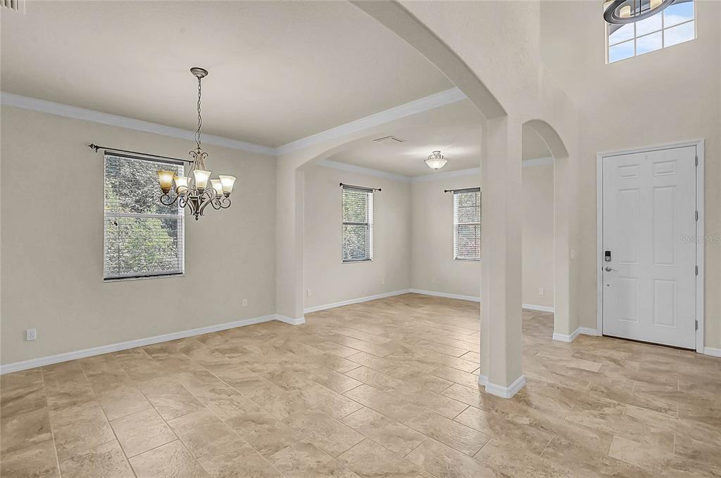 An open-concept dining area features tile flooring, a chandelier, and an arched entryway — 11691 BREADFRUIT LANE, VENICE, FL