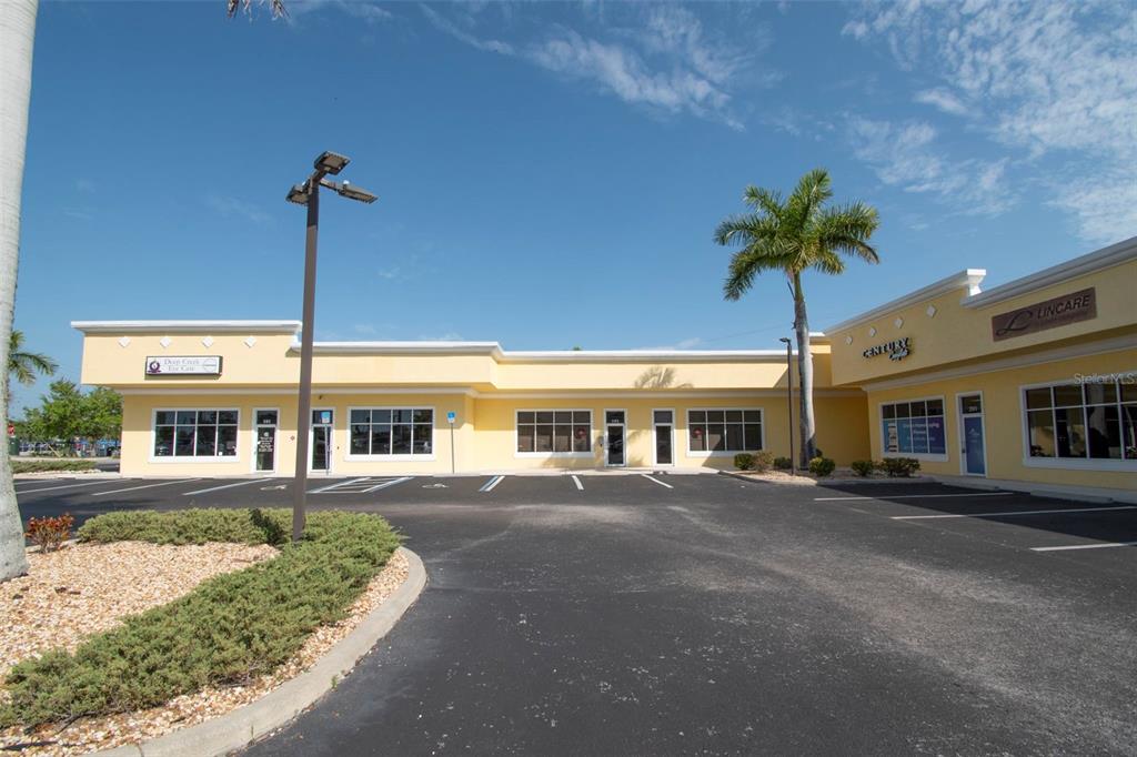 A yellow commercial strip mall building with a parking lot and a palm tree — 24420 SANDHILL BOULEVARD, PUNTA GORDA, FL