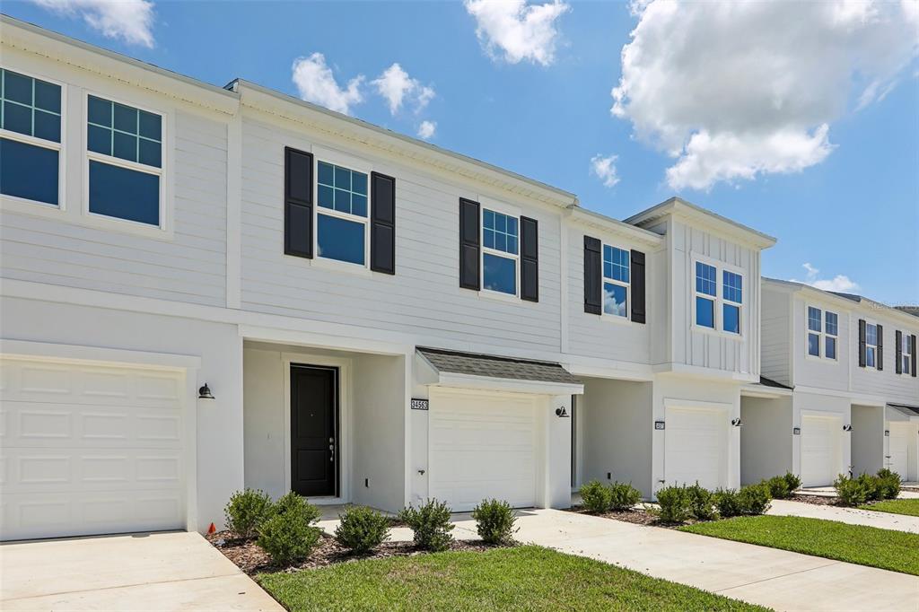 A row of white two-story townhouses with attached garages and small front lawns — 34563 TURPINS AVENUE, ZEPHYRHILLS, FL