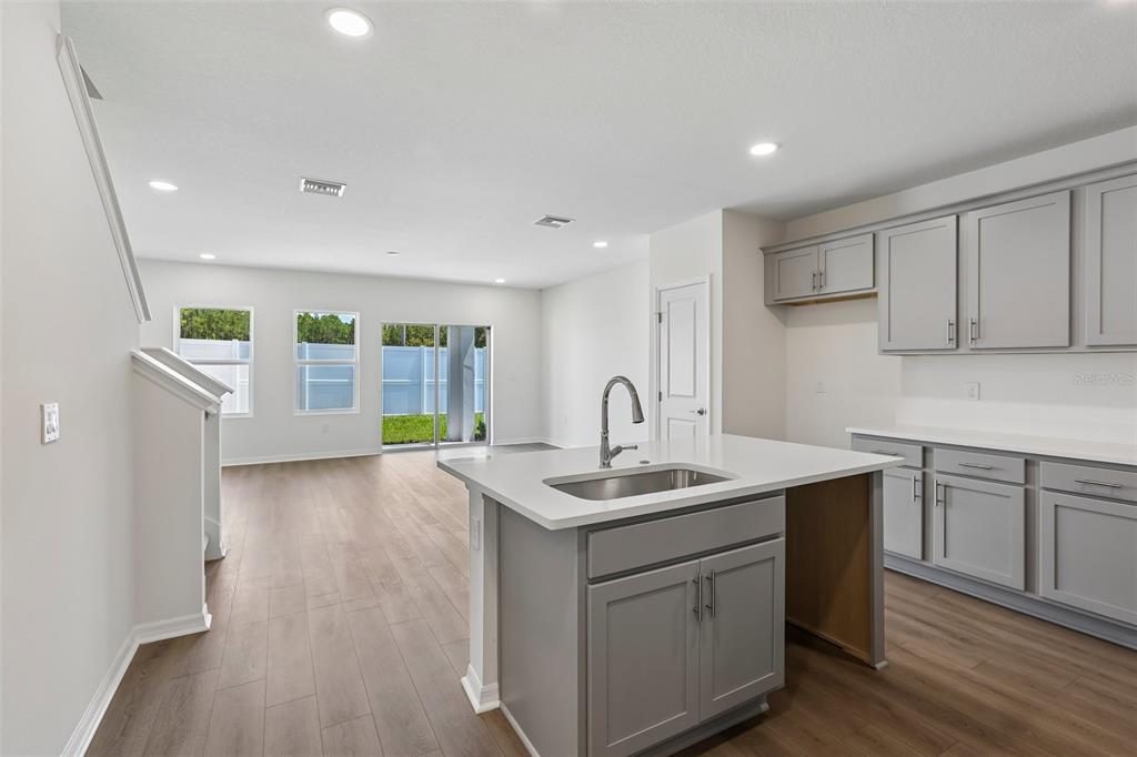 A kitchen with gray cabinets and a white island overlooks an open-concept living area — 34563 TURPINS AVENUE, ZEPHYRHILLS, FL