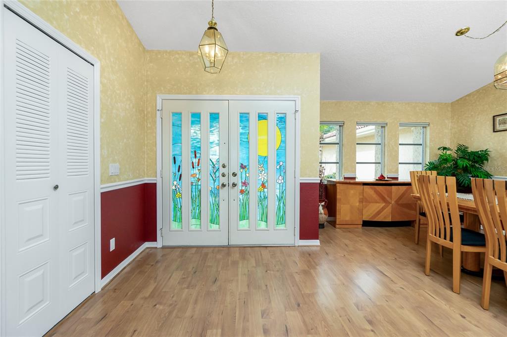 An entryway with light wood flooring, a white louvered closet, and decorative stained glass double doors — 4088 GINGOLD STREET, PORT CHARLOTTE, FL