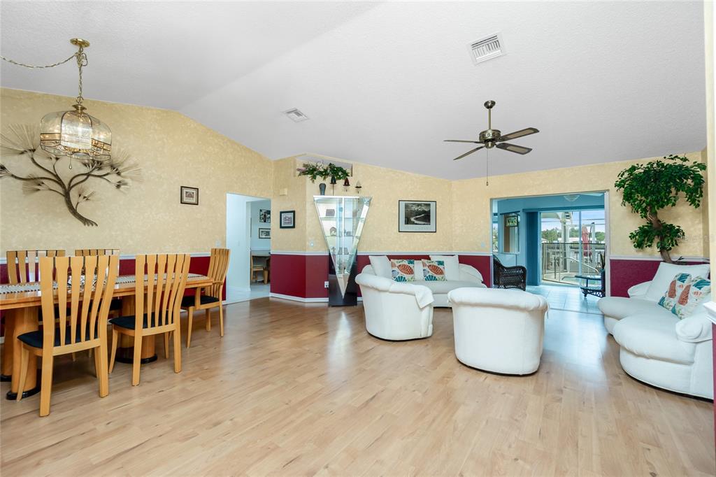 A living and dining area with light wood floors, white furniture, and yellow-painted walls — 4088 GINGOLD STREET, PORT CHARLOTTE, FL
