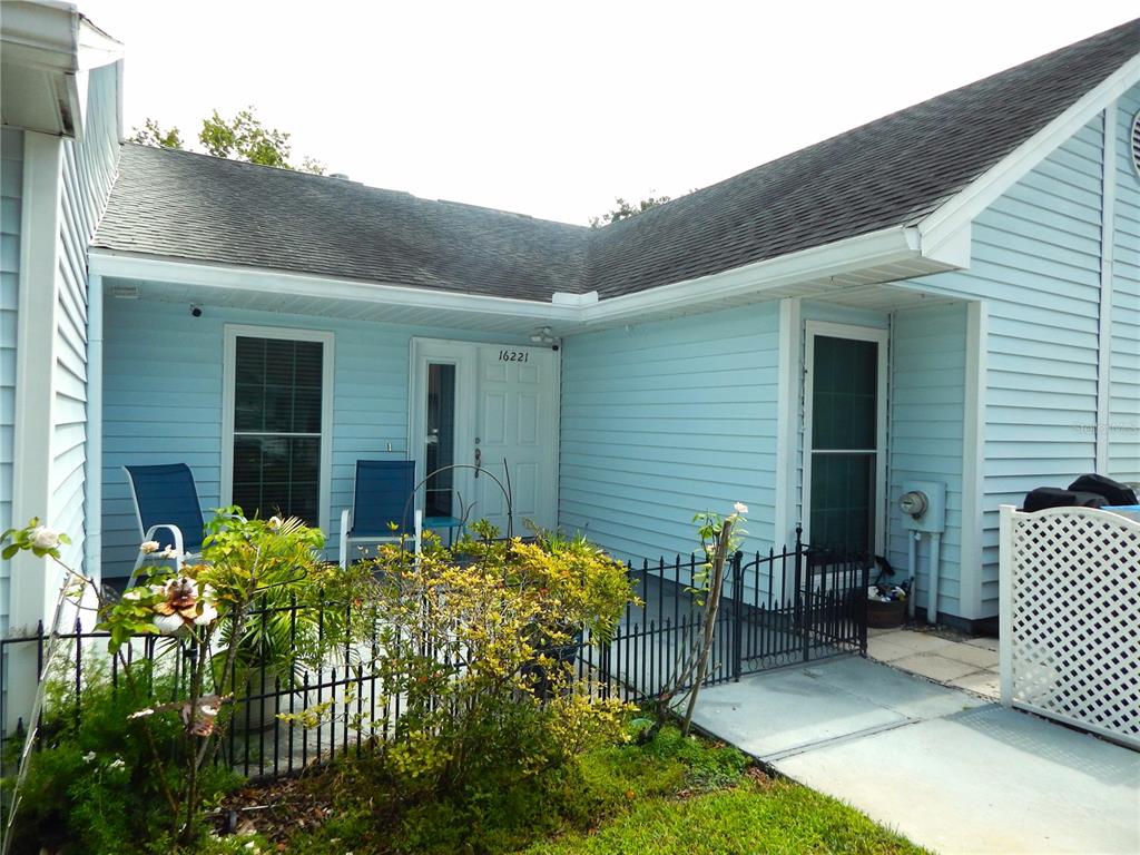 A light blue house exterior features a front patio enclosed by a black metal fence — 16221 RAMBLING VINE DRIVE W, TAMPA, FL