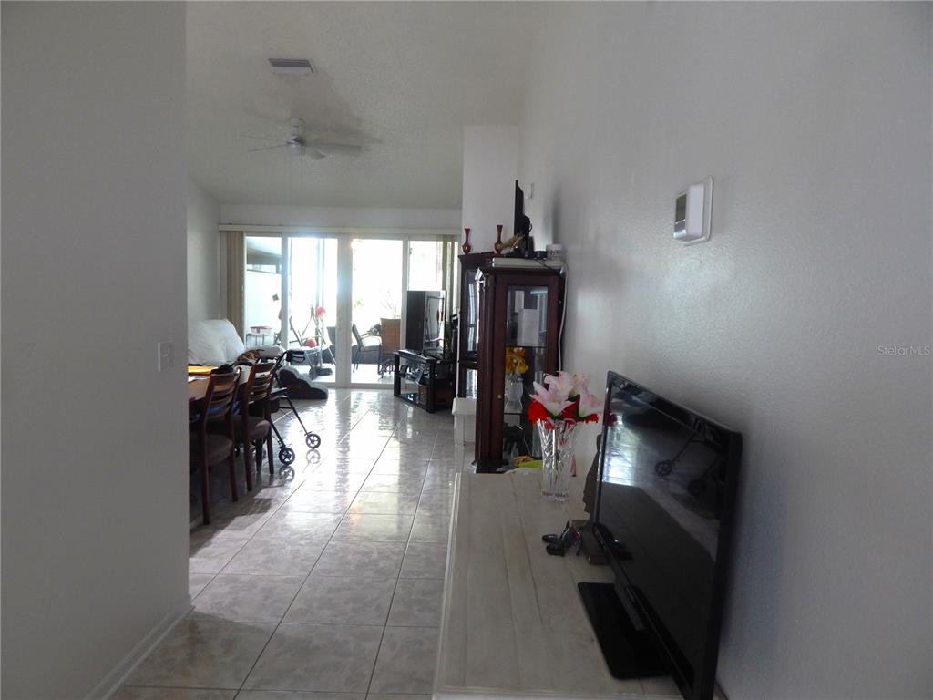 A living and dining area with tile flooring leads to a sliding glass door — 16221 RAMBLING VINE DRIVE W, TAMPA, FL