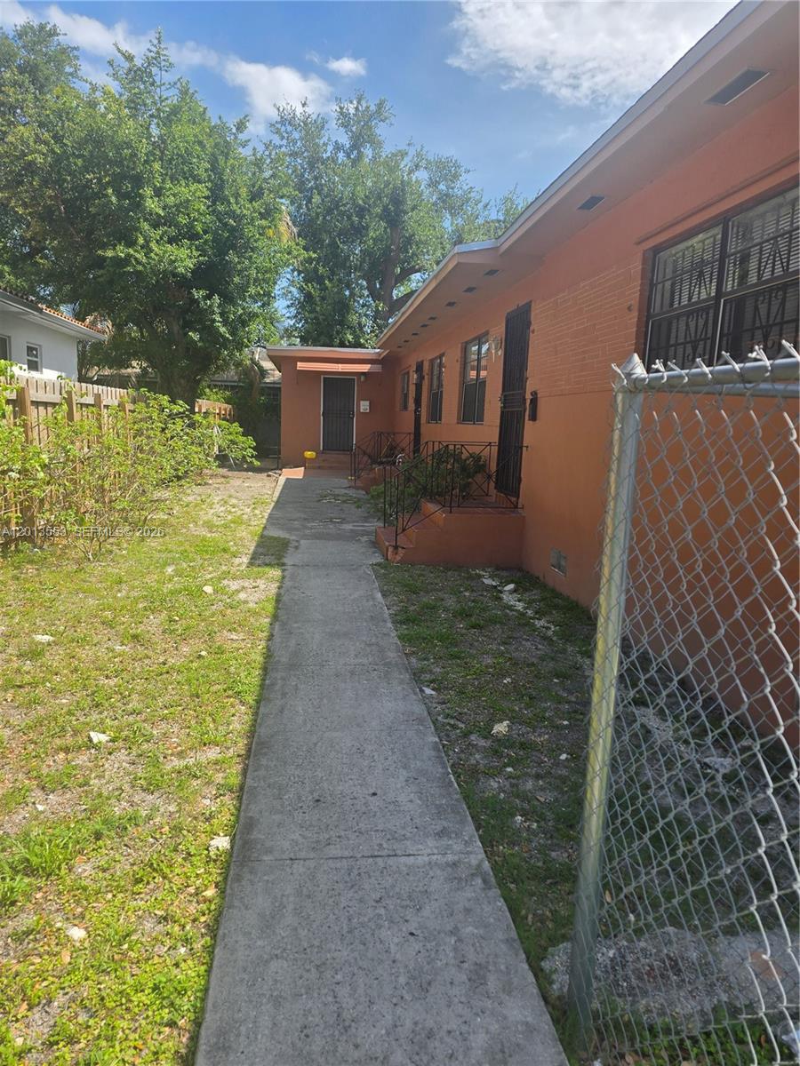 A concrete walkway leads along the side of an orange building with multiple entry doors — 210 NW 69th St # 212, Miami FL 33150, MIAMI, FL