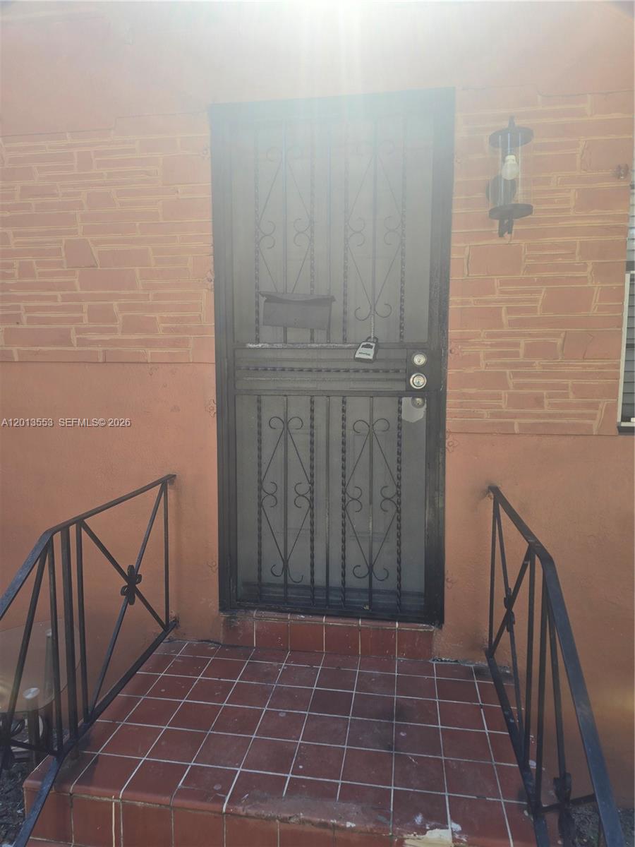 A front entryway features a metal security door, tiled steps, and black iron railings — 210 NW 69th St # 212, Miami FL 33150, MIAMI, FL
