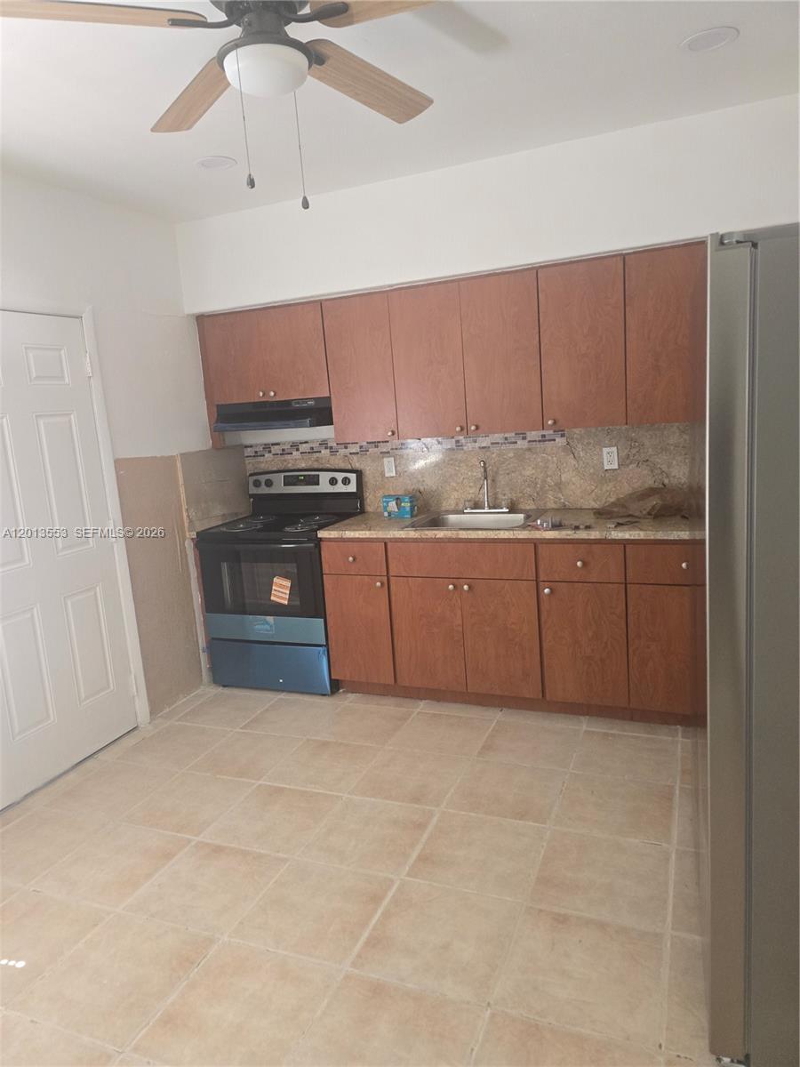 A kitchen features wood cabinets, a stainless steel stove, and a tiled floor — 210 NW 69th St # 212, Miami FL 33150, MIAMI, FL