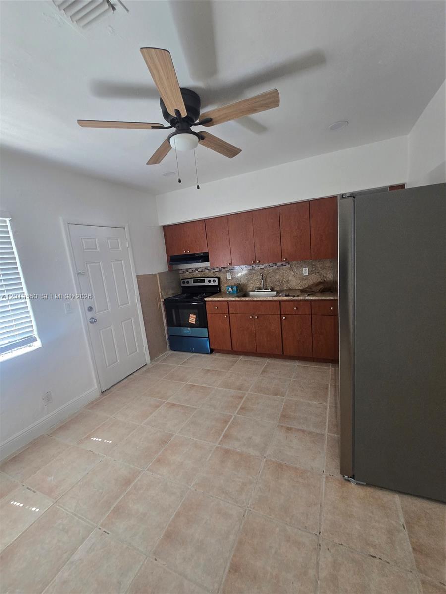 This kitchen features wood cabinets, a stainless steel refrigerator, a stove, and tile flooring — 210 NW 69th St # 212, Miami FL 33150, MIAMI, FL