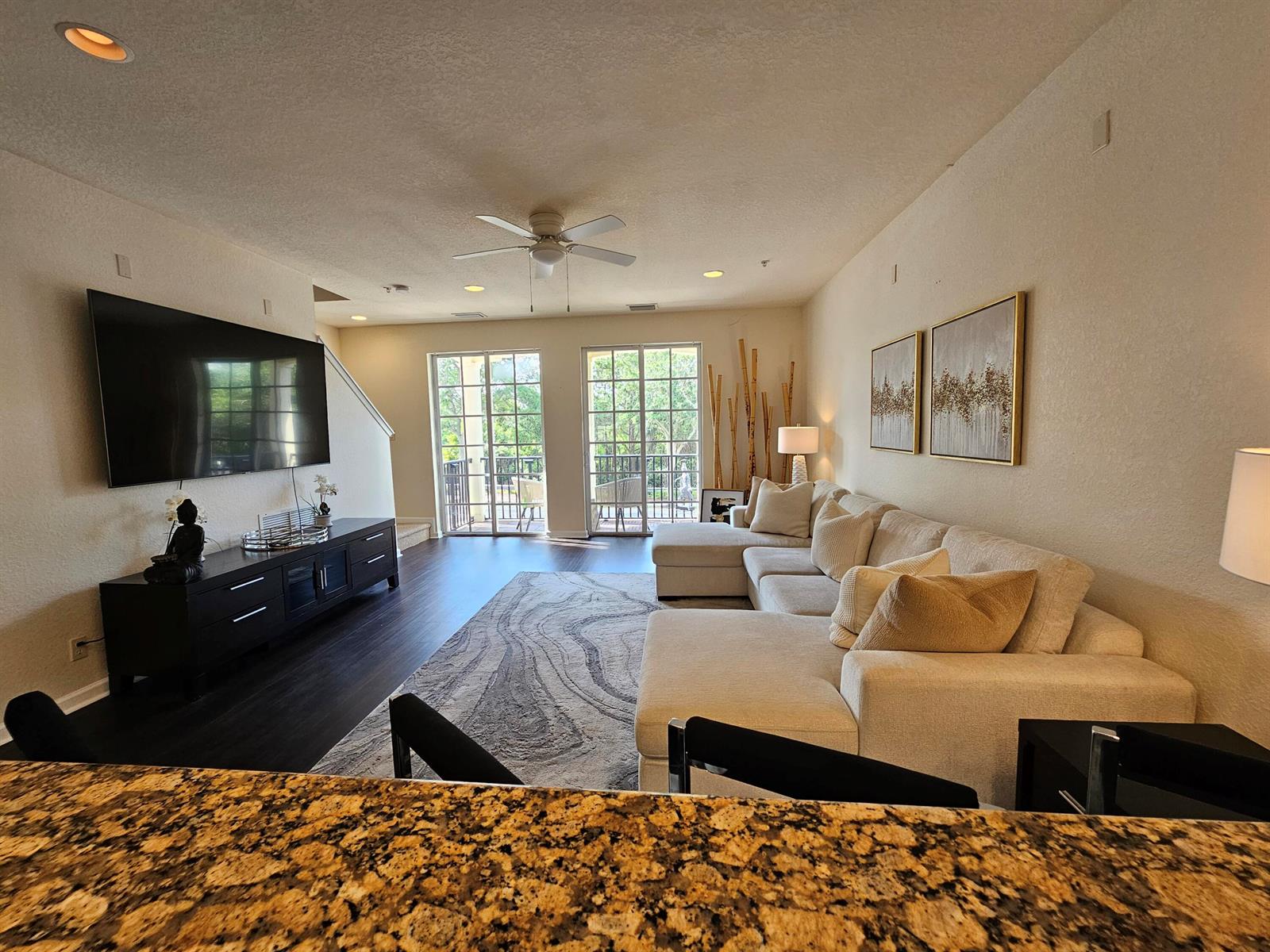 A living room features a large sectional sofa, a wall-mounted television, and sliding glass doors — 405 Schoolhouse Road, Jupiter FL 33458, JUPITER, FL