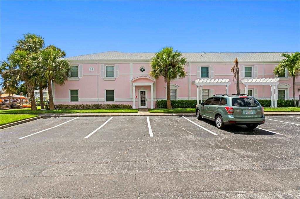 A two-story pink building with a parking lot and palm trees in front — 5175 COQUINA KEY DRIVE SE UNIT A, ST PETERSBURG, FL