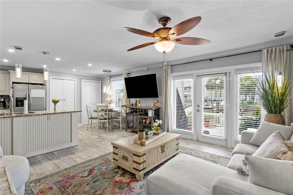 An open-concept living room and kitchen featuring light wood-look tile flooring and a ceiling fan — 5175 COQUINA KEY DRIVE SE UNIT A, ST PETERSBURG, FL