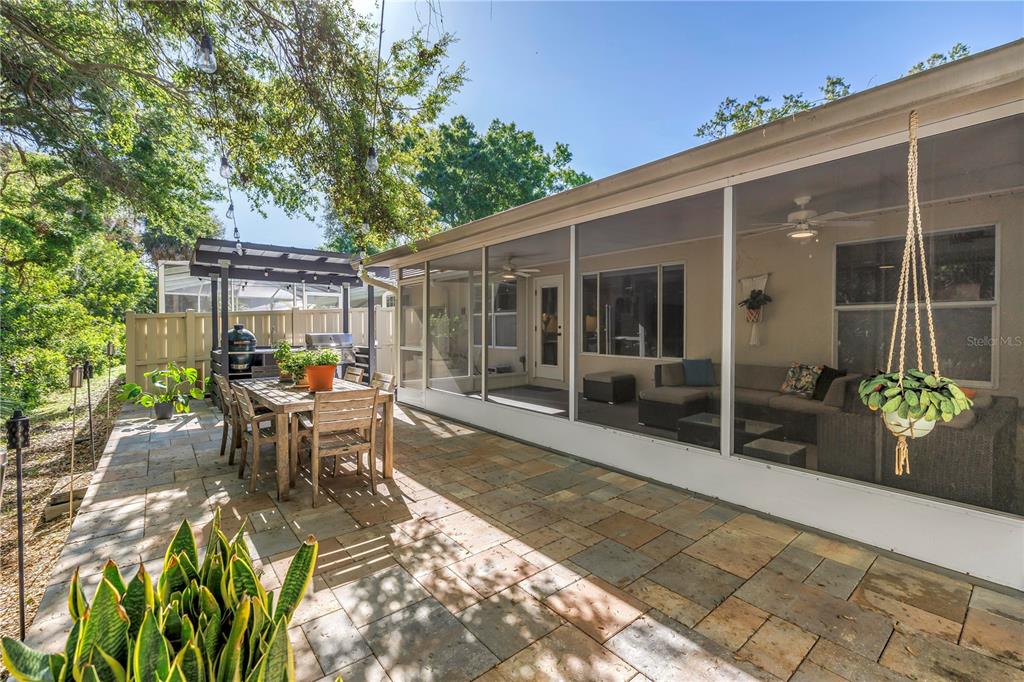 A stone patio features a dining set and a screened-in porch with outdoor seating — 355 RED CEDAR COURT NE, ST PETERSBURG, FL